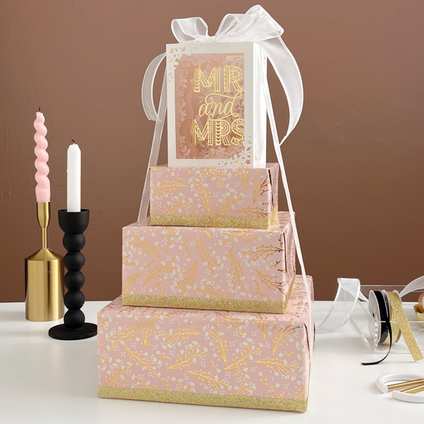 A gift tower wrapped for a wedding, topped with a