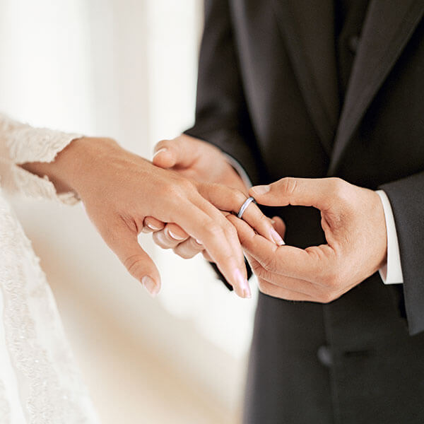 A groom putting a ring on the bride's finger.