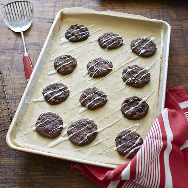 Lebkuchen cookies with a drizzle of glaze resting on a baking pan.