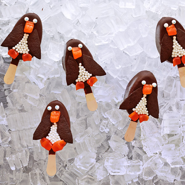 Penguin ice cream bars made from chocolate-covered ice cream bars, chocolate wafer wings and candy beaks, eyes, and body details.