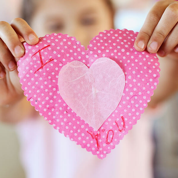 A girl holding a pink paper heart that says