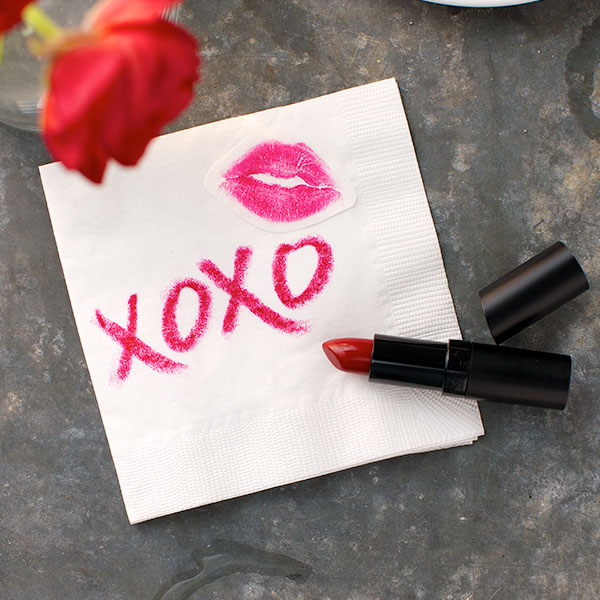 A napkin with XOXO written in pink lipstick and a lipstick print.
