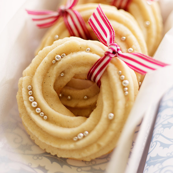 Light-colored Danish butter cookies shaped like wreaths, tied with red and white striped ribbons.