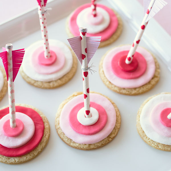 Valentine's Day sugar cookies in red, pink and white to look like targets, decorated with straws to look like arrows.