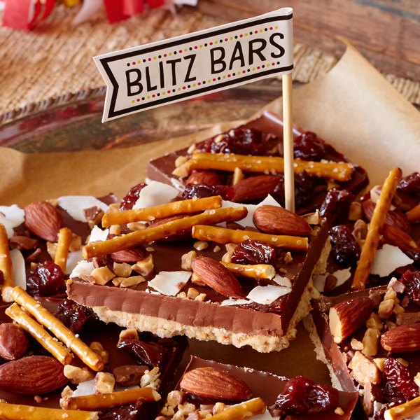 Chocolate coconut bars with salted pretzel crust, pretzel and nut garnish and a flag that says 