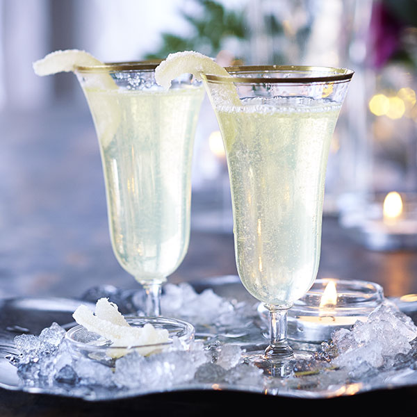 Fizzy limoncello cocktails in champagne flutes with candied lemon peel garnish.