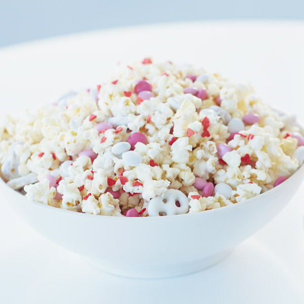 Valentine snack mix with white chocolate coating, mixed with pink heart sprinkles, chocolate candies and white chocolate pretzels.