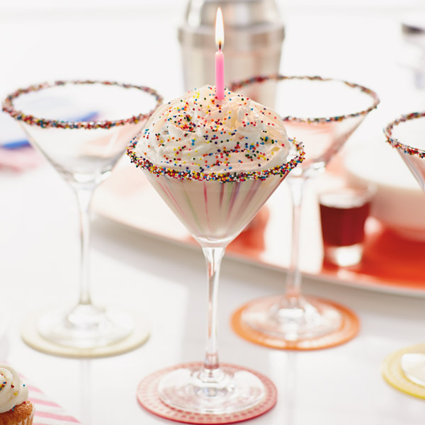 Birthday cake martini with whipped cream, sprinkles and a pink candle.