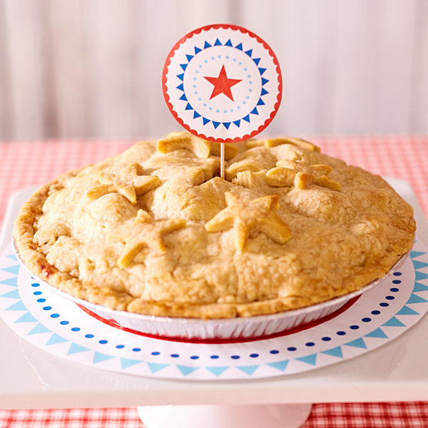 Pink lady apple pie with golden crust embellished with stars and a patriotic dessert topper.