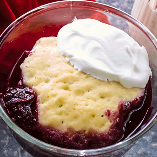 Blackberry slump with fruit mixture, a tender biscuit and fresh whipped cream on top.