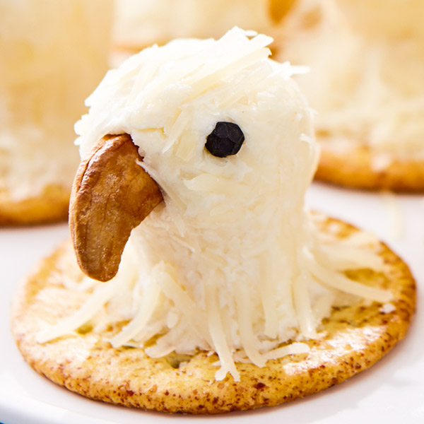 Bald eagle cheese bite on a cracker with a cashew beak and peppercorn eye.