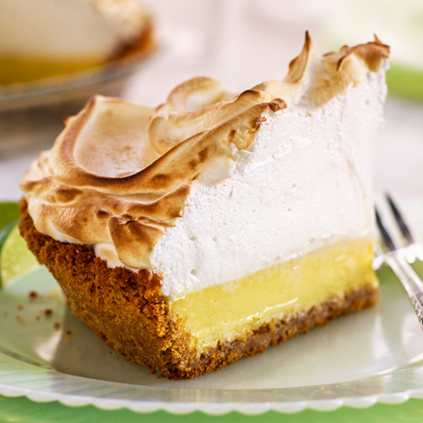Key lime pie with a thin layer of filling and a thick layer of meringue browned on top.