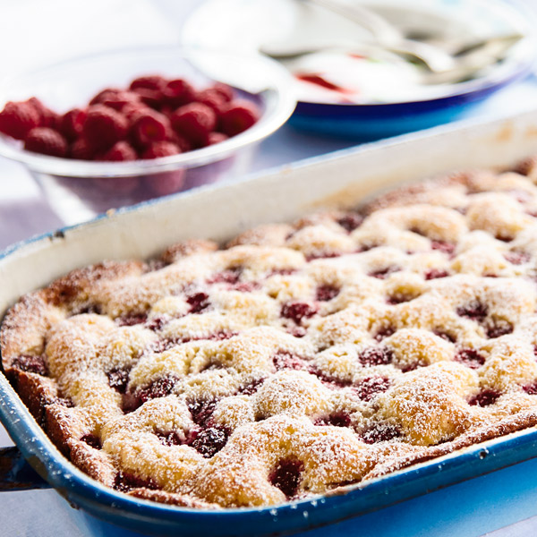 Raspberry buckle cake with indentations of raspberries, topped with powdered sugar.