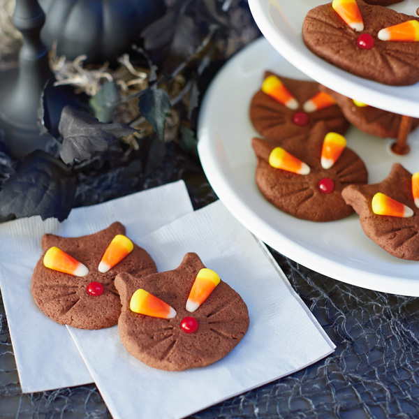 Cat cookies with candy corn eyes, chocolate nose and marks for whiskers.