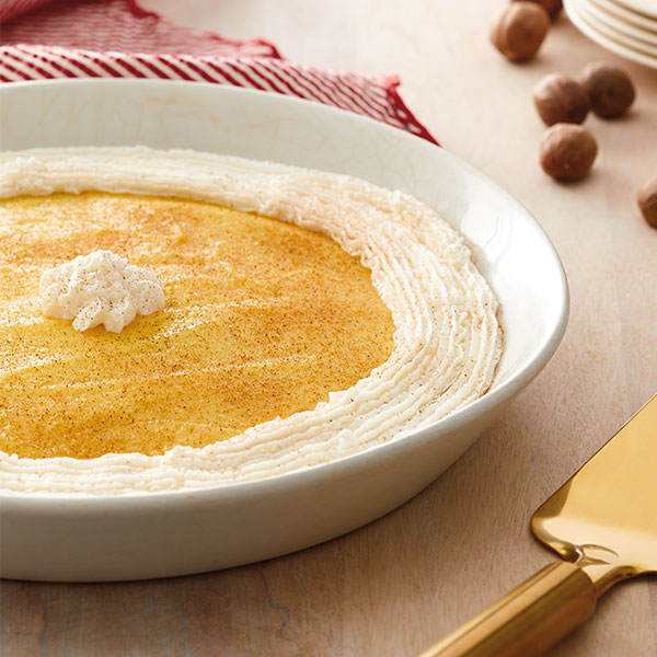 Egg nog pie with gingerbread crust with a ring of whipped cream around the outside and one dollop of whip in the middle.