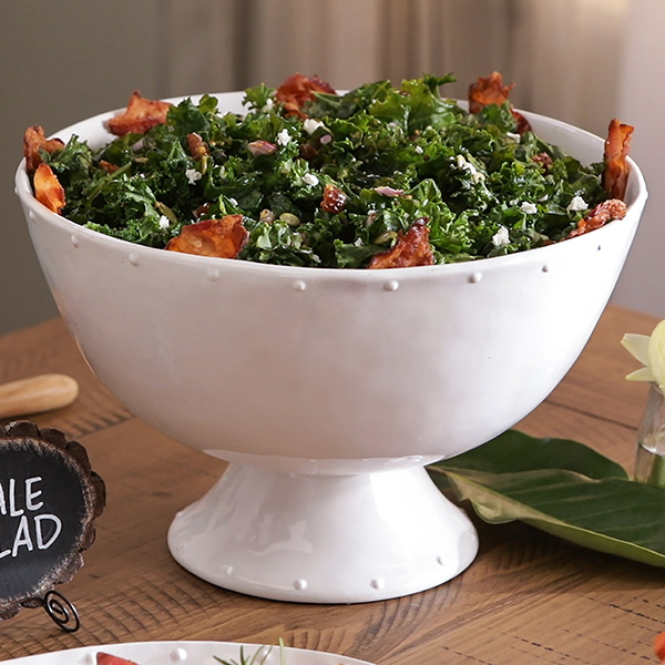 Warm kale salad with bacon dressing and bacon pieces in a serving bowl.