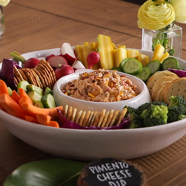Pimento cheese dip on a serving tray with assorted vegetables and crackers.