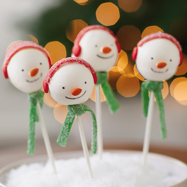 Four snowman cake pops with green scarves and red earmuffs.