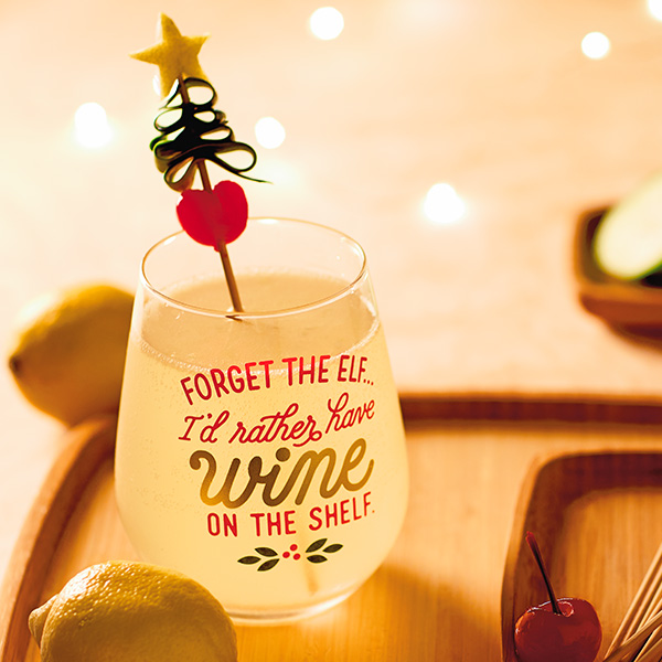 Holiday sparkler in a holiday stemless wine glass and a cucumber Christmas tree garnish.