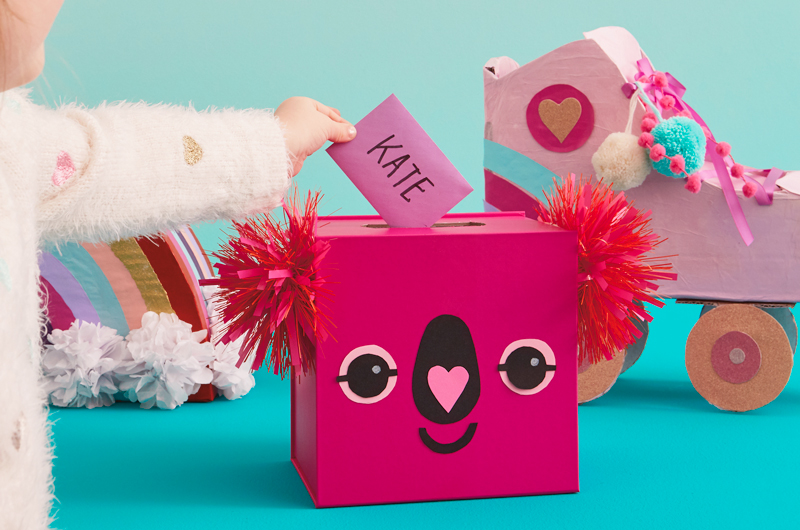 DIY Koala Valentine Box with childs hand on table with other Valentines