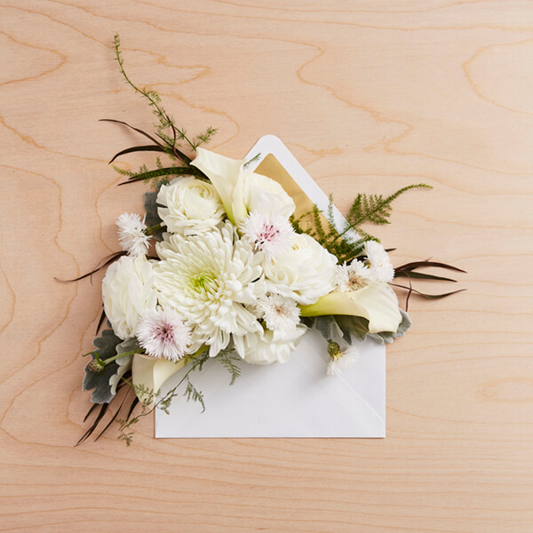 Sympathy card in envelope on table with flowers