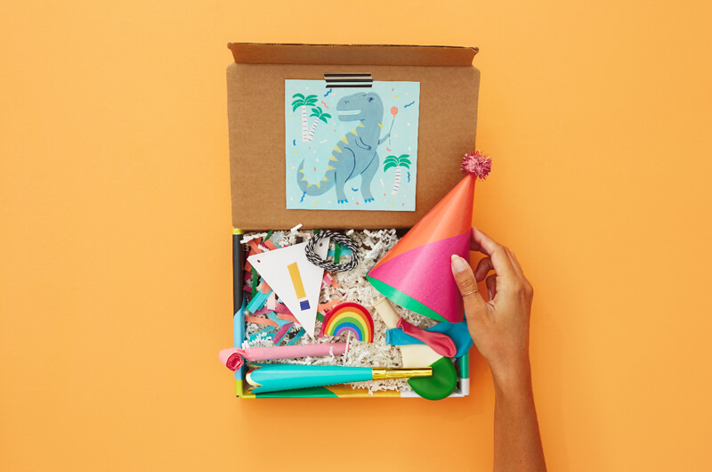 Hand putting birthday hat in birthday care package