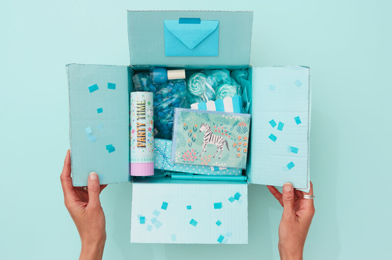 Hands holding a blue birthday care package