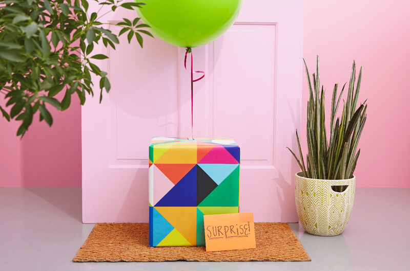 Birthday care package in front of door with balloon and envelope