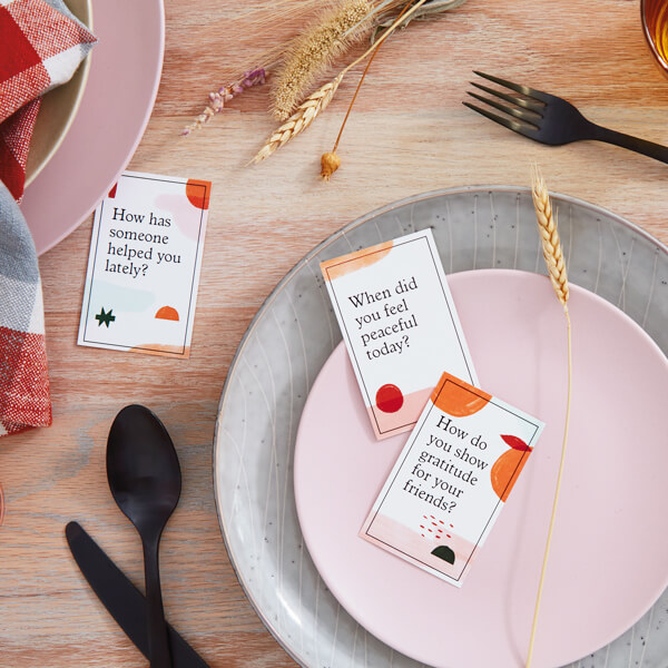 Gratitude conversation cards on a table setting with flatware and some wheat