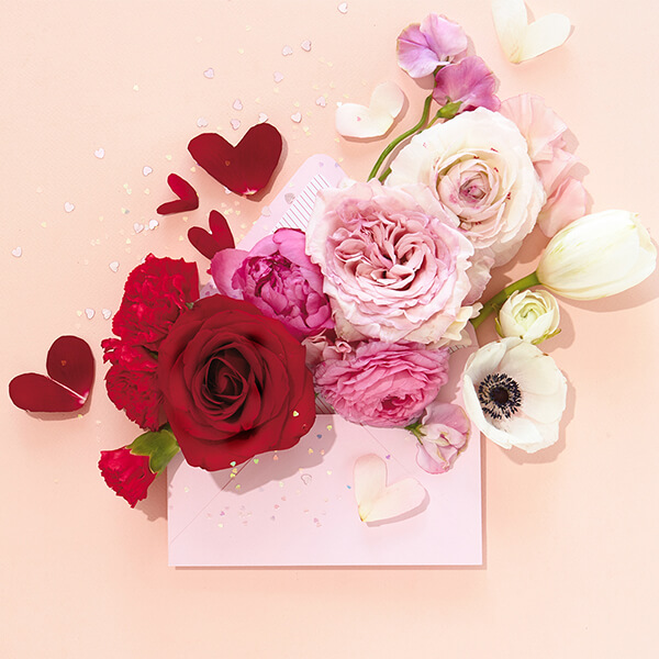 A love letter decorated with various flowers and petals in the shape of a heart.