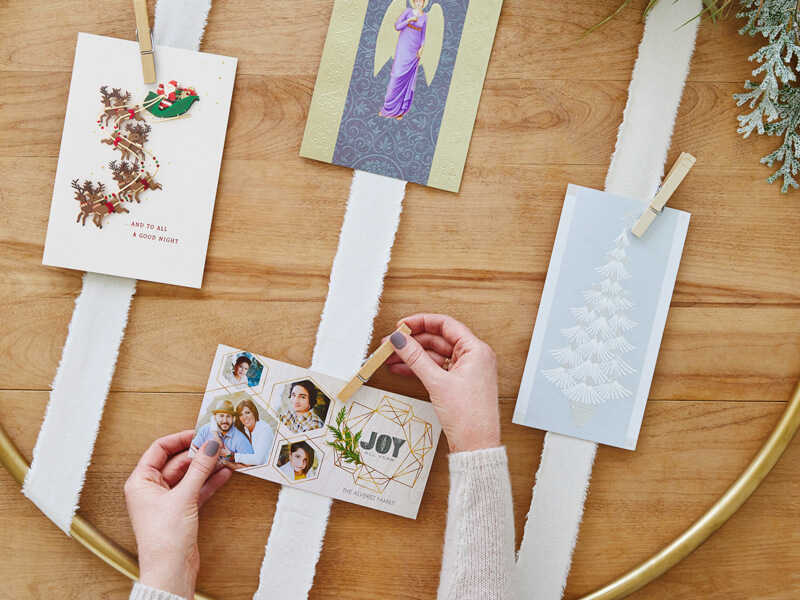 Clothespins being attached to the card holder and hands placing Christmas cards in it.