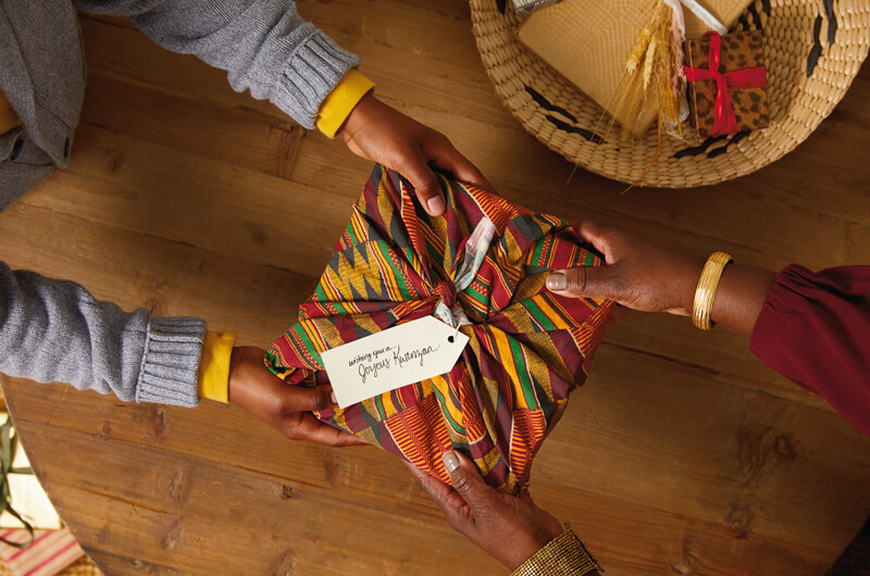Hands exchanging a Kwanzaa present.