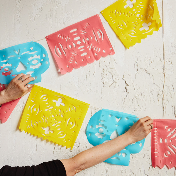 Papel picado on white background with hands.