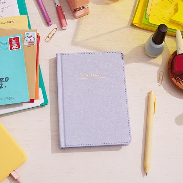 Address book with chambray cover on desktop with envelopes and office accessories