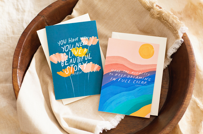 Two cards from the Morgan Harper Nichols Real Stories Collection in a wooden bowl. One reads,