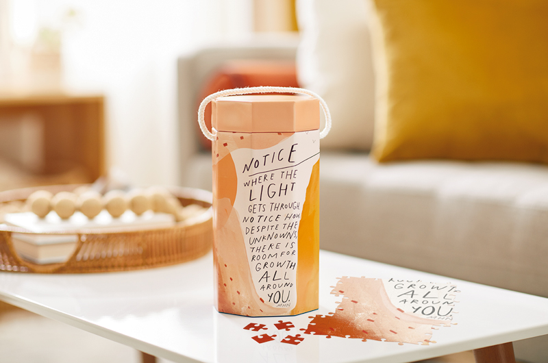 A partially put-together puzzle from the Morgan Harper Nichols Real Stories Collection with its decorative container.