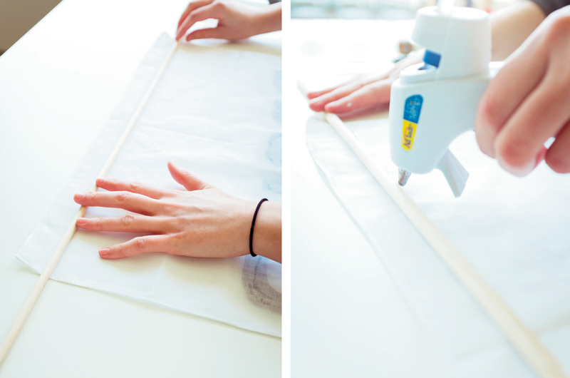 Hands placing a dowel rod on a flag, then applying hot glue to the dowel before folding the flag over it to adhere.