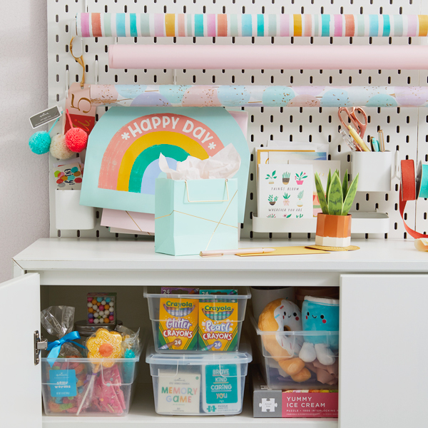 A bright and colorful gift closet setup for kids, with Crayola crayons, Better Together plushes, candy, ribbons and a confetti-patterned card organizer.