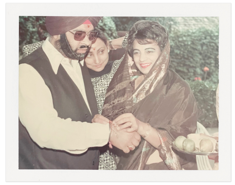 A young woman in traditional Indian garb ties a rakhi bracelet around her brother's wrist in celebration of Raksha Bandhan, circa 1970.