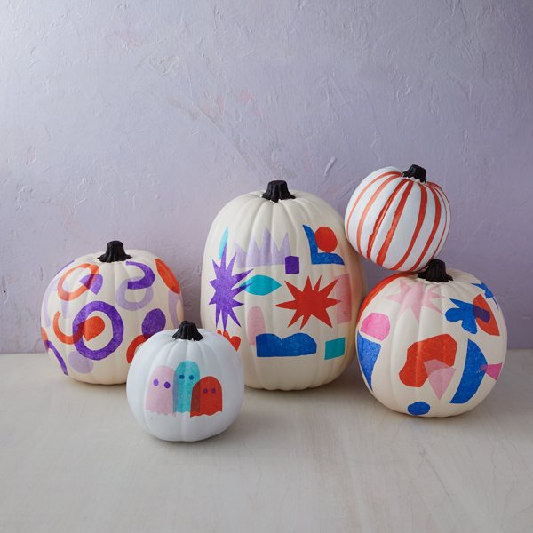 Five finished tissue paper decoupage pumpkins arranged on a wooden surface.