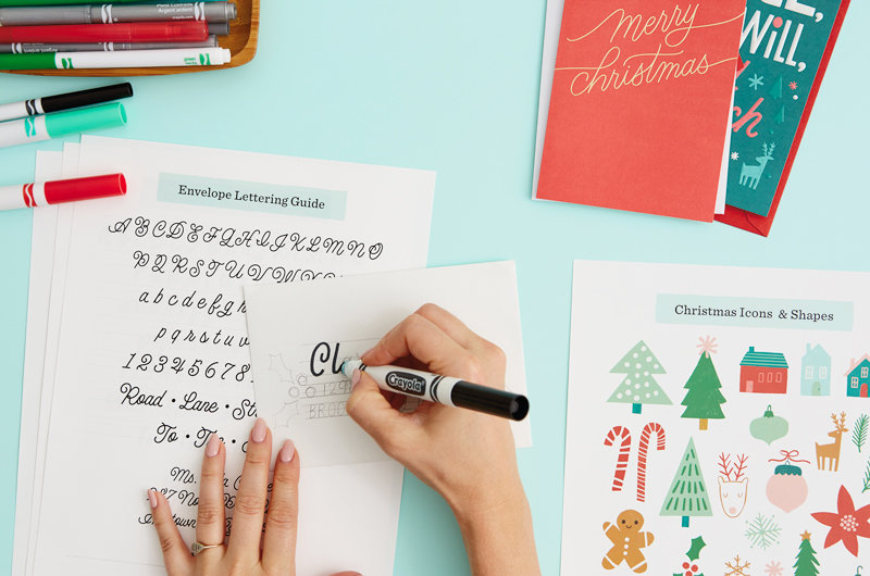 A woman's hands tracing over her penciled letters with a black marker.