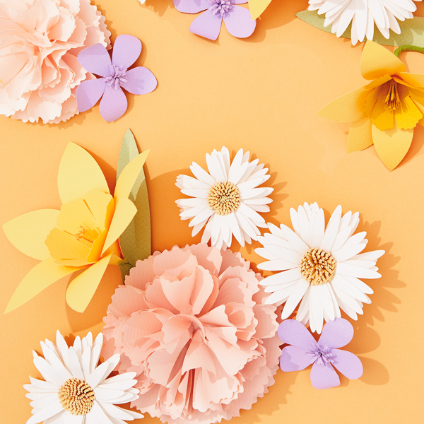 A scattering of flowers crafted entirely out of paper, including carnations, daffodils, asters and violets.