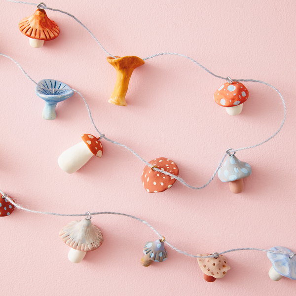 A completed DIY mushroom garland, made with air-dry clay that's been molded and painted to look like mushrooms, some jump rings, and twine.