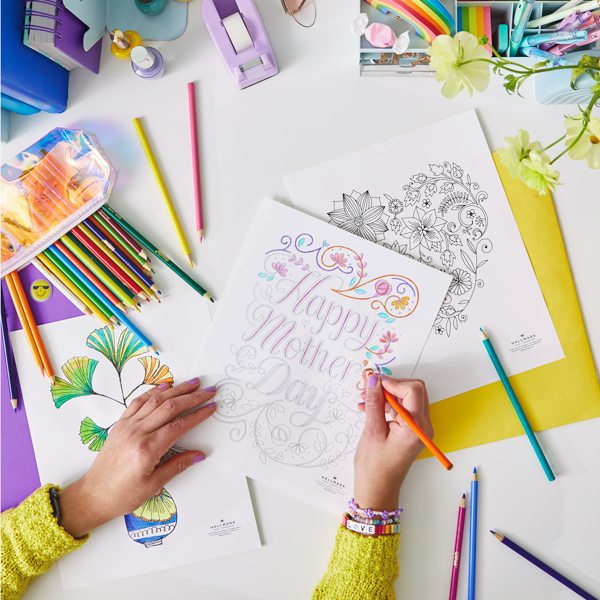 A woman's hands coloring an intricately designed free printable Mother's Day coloring page that reads,