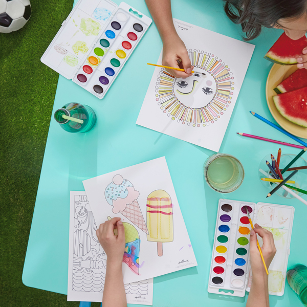 Children painting and coloring our free printable summer coloring pages with watercolors and colored pencils; a little girl nearby takes a bite out of a slice of watermelon.