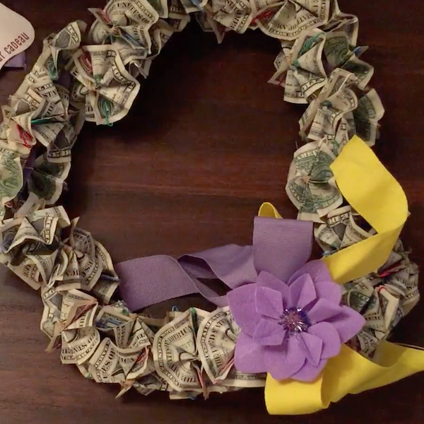 A money lei created with ribbon, a gift wrap bow and folded one dollar bills.
