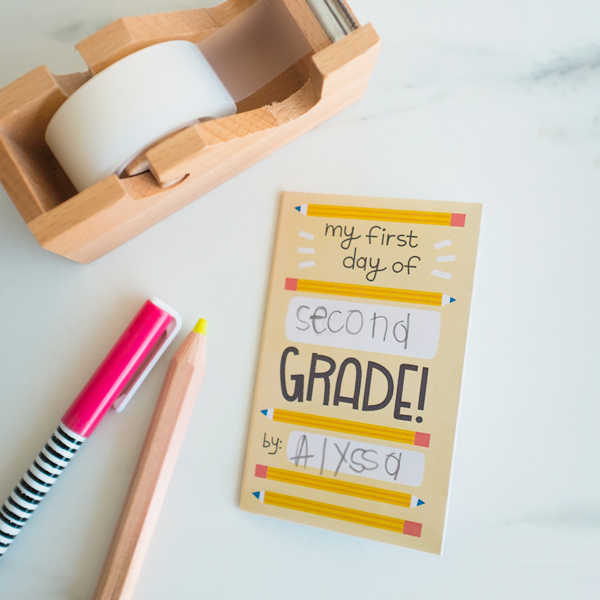 A finished back-to-school zine lays on a white marble countertop next to a tape dispenser, a yellow colored pencil and a pen.