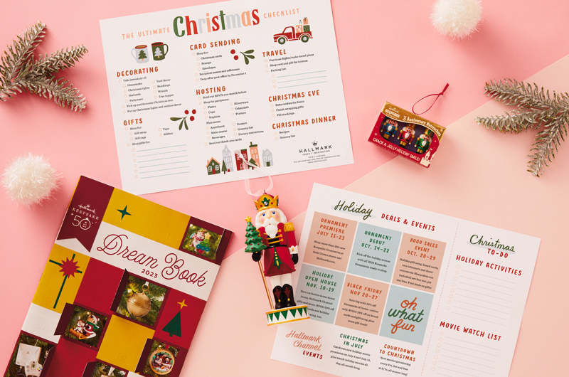 Our free, printable, ultimate Christmas to-do list lying on a light pink surface, surrounded by silver tinsel and Hallmark Keepsake Ornaments.