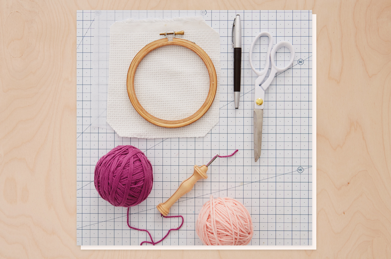 Materials needed for needle punch patches include scissors, a pencil, yarn in your colors of choice, evenweave fabric, fusible interfacing, iron-on patch adhesive (if making patches), and a punch needle.