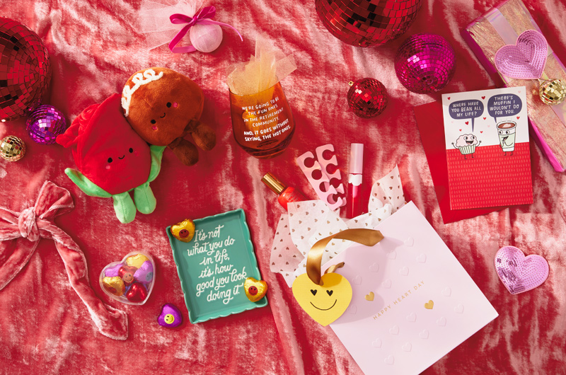 A collection of cute gifts for Galentine's Day, including a Rose and Bon-Bon Better Together pair, a stemless wine glass with a funny quote on the side, a humor card, a trinket dish, and supplies for pedicures.